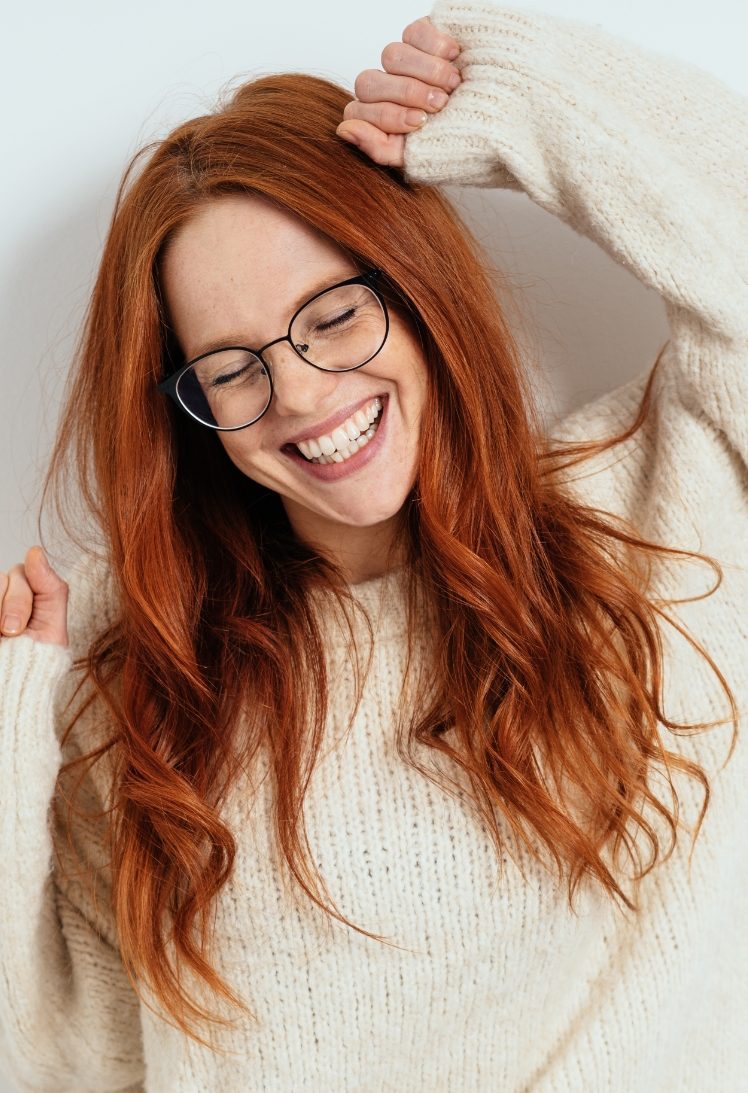 Woman with red hair wearing glasses and a white sweater