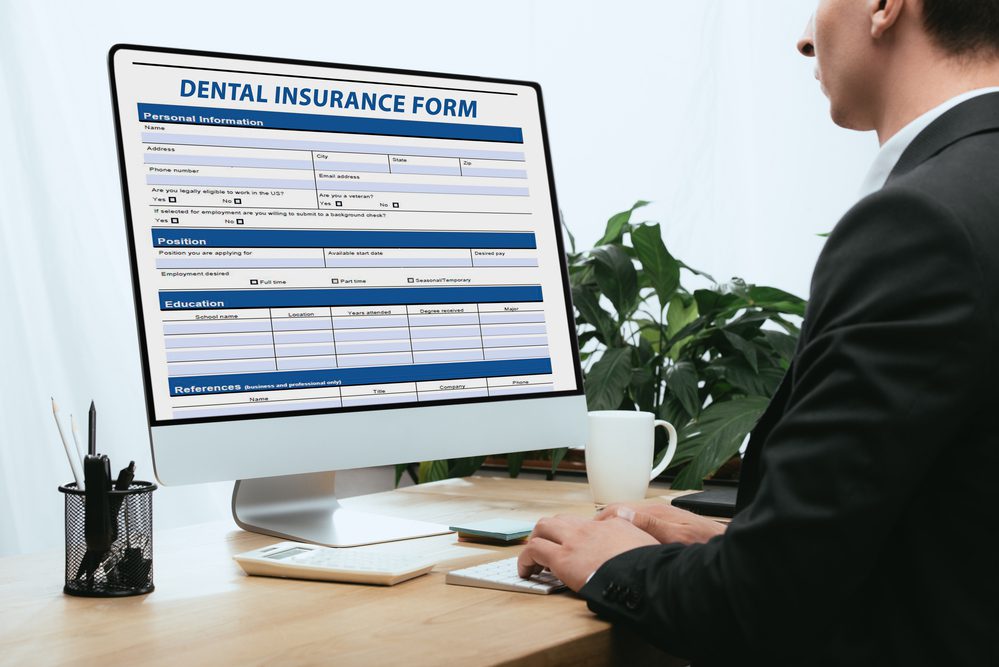 Cropped view of man filling in Dental Insurance Form Dentist